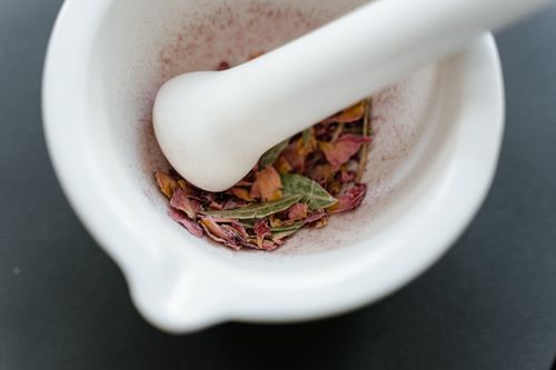 乳鉢と乳棒で乾燥させたバラの花びらをすり潰す