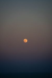 黄昏時の空に浮かぶオレンジ色の満月