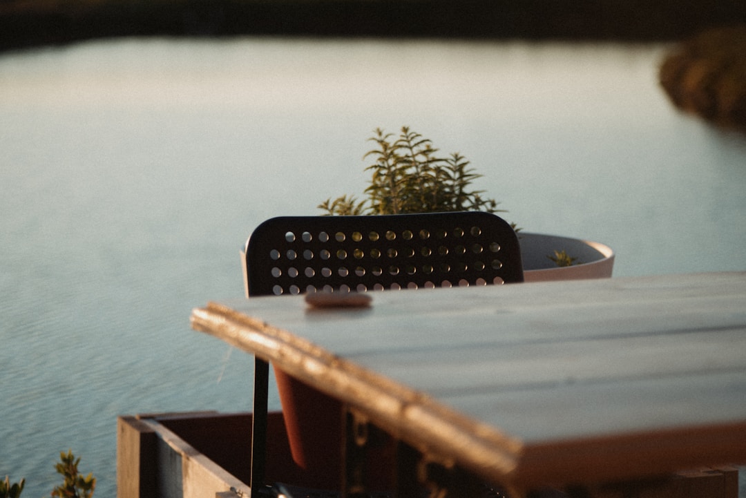 A chair and table overlook calm water.