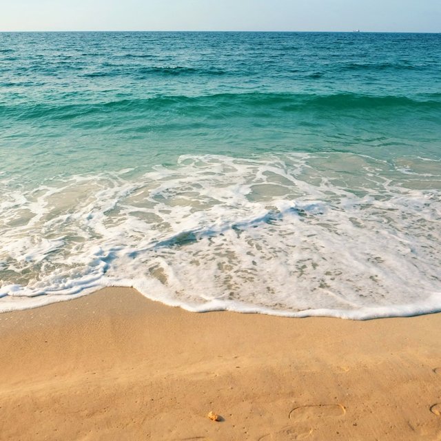 明るい砂浜に寄せる波